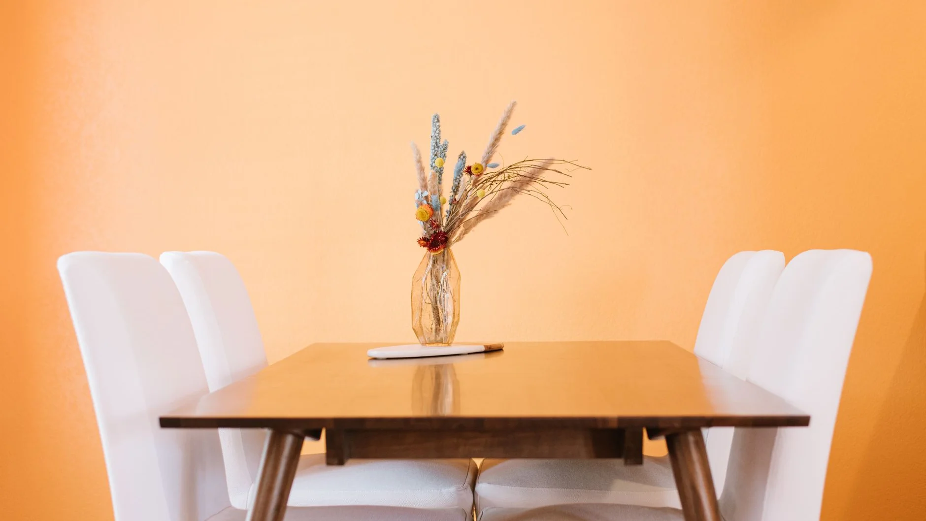 Fotografia referencyjna: Stół ze szklanym wazonem i roślinami dekoracyjnymi w jasnym wnętrzu mieszkalnym yellow wall – proces tworzenia wizualizacji 3D kolekcji mebli krok po kroku